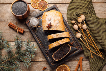 Board with tasty poppy seed strudel and fir branch and ingredients on wooden background