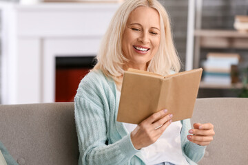 Beautiful mature woman reading book at home on autumn day