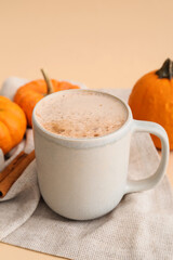 Cup of tasty pumpkin coffee on beige background