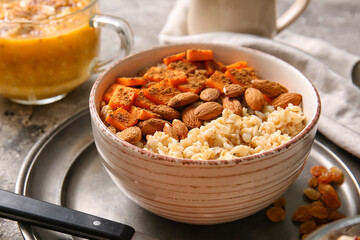 Bowl of tasty oatmeal with pumpkin and almond on grunge background
