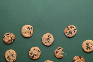 Tasty homemade cookies with chocolate chips on green background