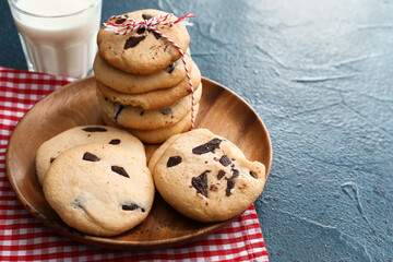 Plate with delicious homemade cookies and glass of milk on dark background