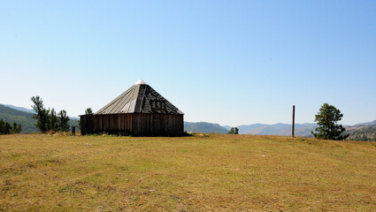 An old wooden yutra on top of a hill overlooking the mountain range.