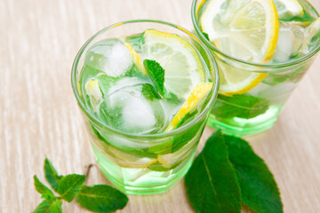 Cool lemonade drink or mojito cocktail with lemon, mint and ice ingredient on golden table
