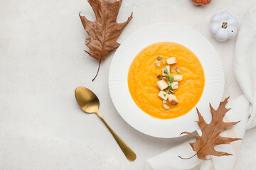 Composition with plate of tasty pumpkin cream soup and autumn leaves on white background