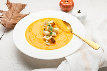 Plate of tasty pumpkin cream soup on white background