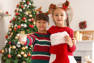 Cute little children with Christmas sock and gift in living room