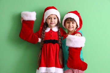 Cute little children with Christmas socks on color background