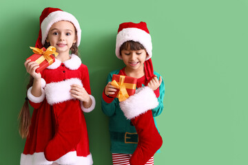Cute little children with Christmas socks and gifts on color background
