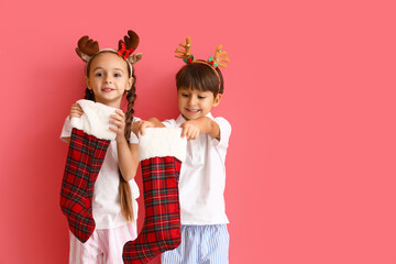 Cute little children with Christmas socks on color background