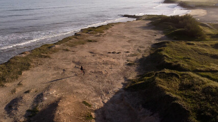 Aerial view of people walking on top of big cliffs during sunset at Mar del Plata Cliff in Argentina