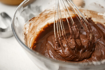 Bowl with fresh chocolate dough on white wooden background, closeup