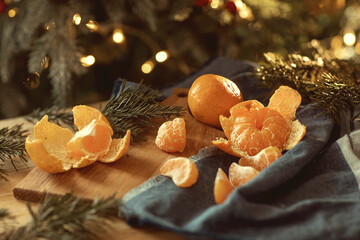 The atmosphere of Christmas, tangerines among the Christmas tree branches against the background of lights.