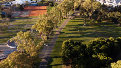 Aerial shot of car driving on park path in Parque Sarmiento during sunset,Buenos Aires.