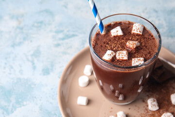Glass of tasty hot chocolate with marshmallows on blue background