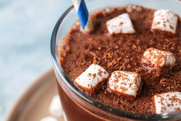 Glass of tasty hot chocolate with marshmallows on blue background, closeup