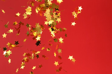 Flying confetti in shape of stars on red background