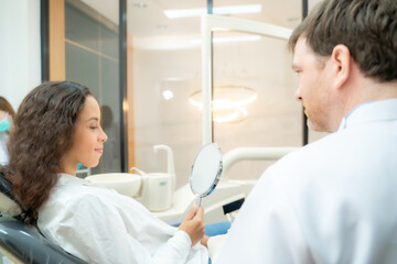 Obraz premium Beautiful woman checking teeth after curing teeth in dental clinic,Woman looking at mirror with smile.