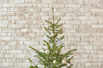 Beautiful Christmas tree decorated with snowflakes and balls on beige brick background, closeup