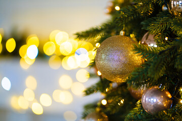 decorated branch of Christmas tree against background of light bulbs of garland.