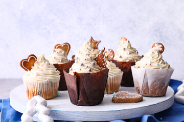 Wooden board with delicious Christmas cupcakes on table