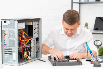 Fototapeta na wymiar computer repair shop. professional services. a man repairs motherboard