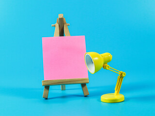 pink sticky note book and stand lamp with easel on background