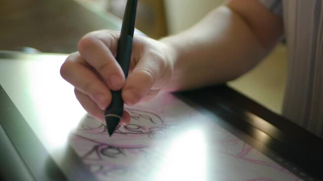 A caucasian woman's hand draws a digital illustration on a tablet in slow motion.