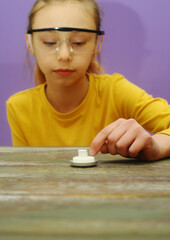  girl with protective eyeglasses makes science experiment at home with water and crystals