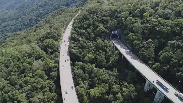Aerial landscape of landmark highway road at green forest trees and mountains. Traffic at famous road way to brazilian south coast. Legendary engineering construction. Brazilian road landmark.