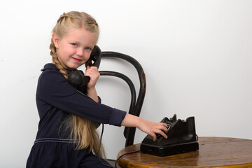 Blonde girl talking by old black phone