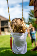 Young Caucasian girl on a swing with long blond hair blowing in the wind