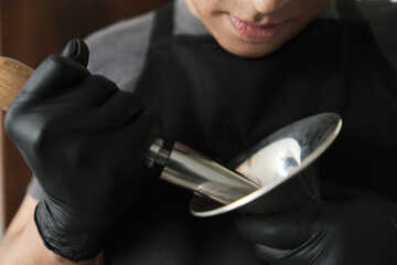 Latino man removing dents from a trumpet bell with metal roller © Oscar Giraldo
