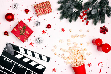 Movie clapper board with Christmas decorations, gifts and popcorn on white background.