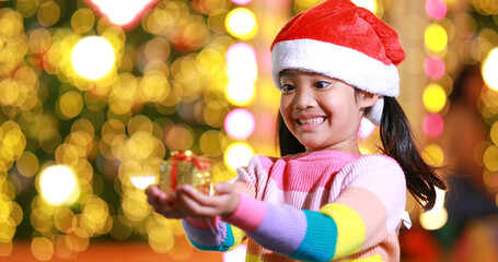 New year anticipation.The cute little girl Wearing a red Christmas hat and beautiful color shirt on a christmas background with bokeh lights .Have fun and have fun during this important season.