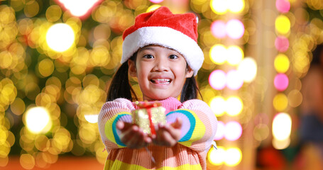 Fototapeta na wymiar New year anticipation.The cute little girl Wearing a red Christmas hat and beautiful color shirt on a christmas background with bokeh lights .Have fun and have fun during this important season.