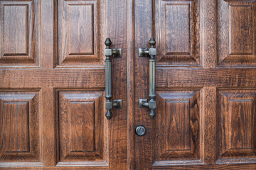 Large wooden door with big vertical handles . Entrance concept