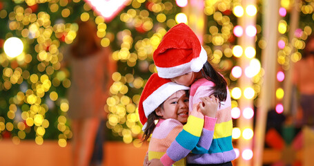 New year anticipation.Two cute little girl Wearing a red Christmas hat and beautiful color shirt on a christmas background with bokeh lights .Have fun and have fun during this important season.