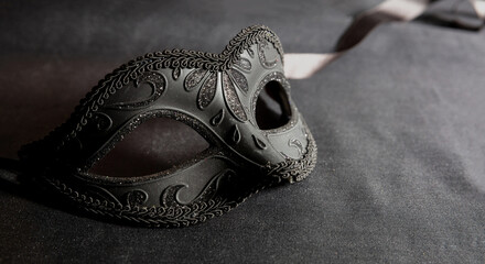 Carnival Venetian black mask on dark grey color background, female disguise, masquerade