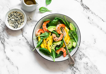 Fresh asian style salad with shrimp, mango, spinach and avocado on a light background, top view