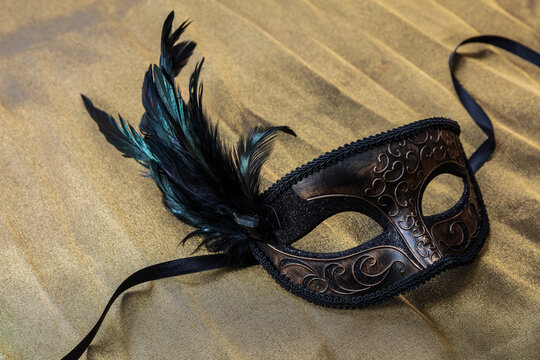 Carnival Venetian mask with feathers on golden color background, female disguise, masquerade