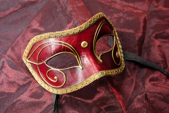 Carnival Venetian red mask on red color fabric background, disguise, masquerade