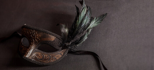 Carnival party. Venetian female mask with feathers on black color background, masquerade, copy space