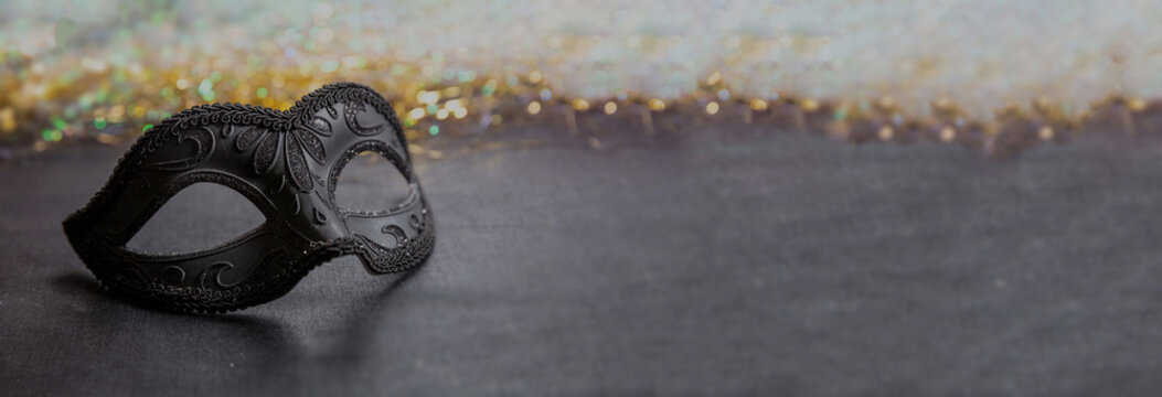 Carnival Venetian black mask on dark grey color background, female disguise, masquerade