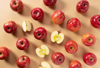 A lot of apples placed on a beige background, cut in half or quarter.