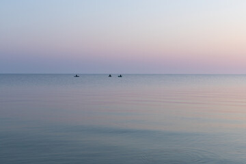 Sea at dawn with three fishing rubber boats, calm, Sea of Azov, Russia.