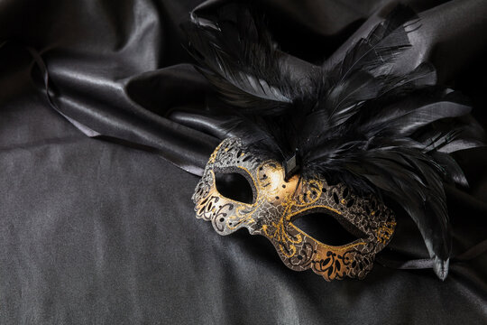 Carnival Venetian golden mask with feathers on black color background, female disguise, masquerade