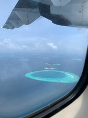 Aerial view of the Maldives in the turquoise water of the Indian Ocean from the porthole from under the wing of a local airlines plane.