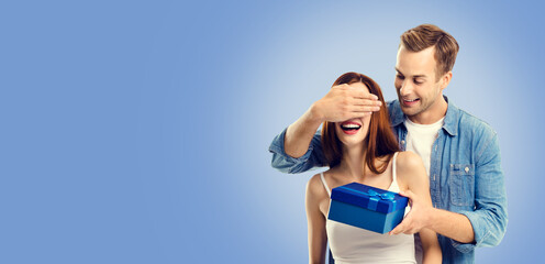 Love, holiday sales, shop, rebates, discounts offers concept - happy amorous couple with blue gift box. Blue color background. Copy space for text. Valentines Day.