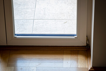 Indoor and outdoor floor surface closeup. Wooden texture and ceramics. Window glass between different patterns. Selective focus on the details, blurred background.